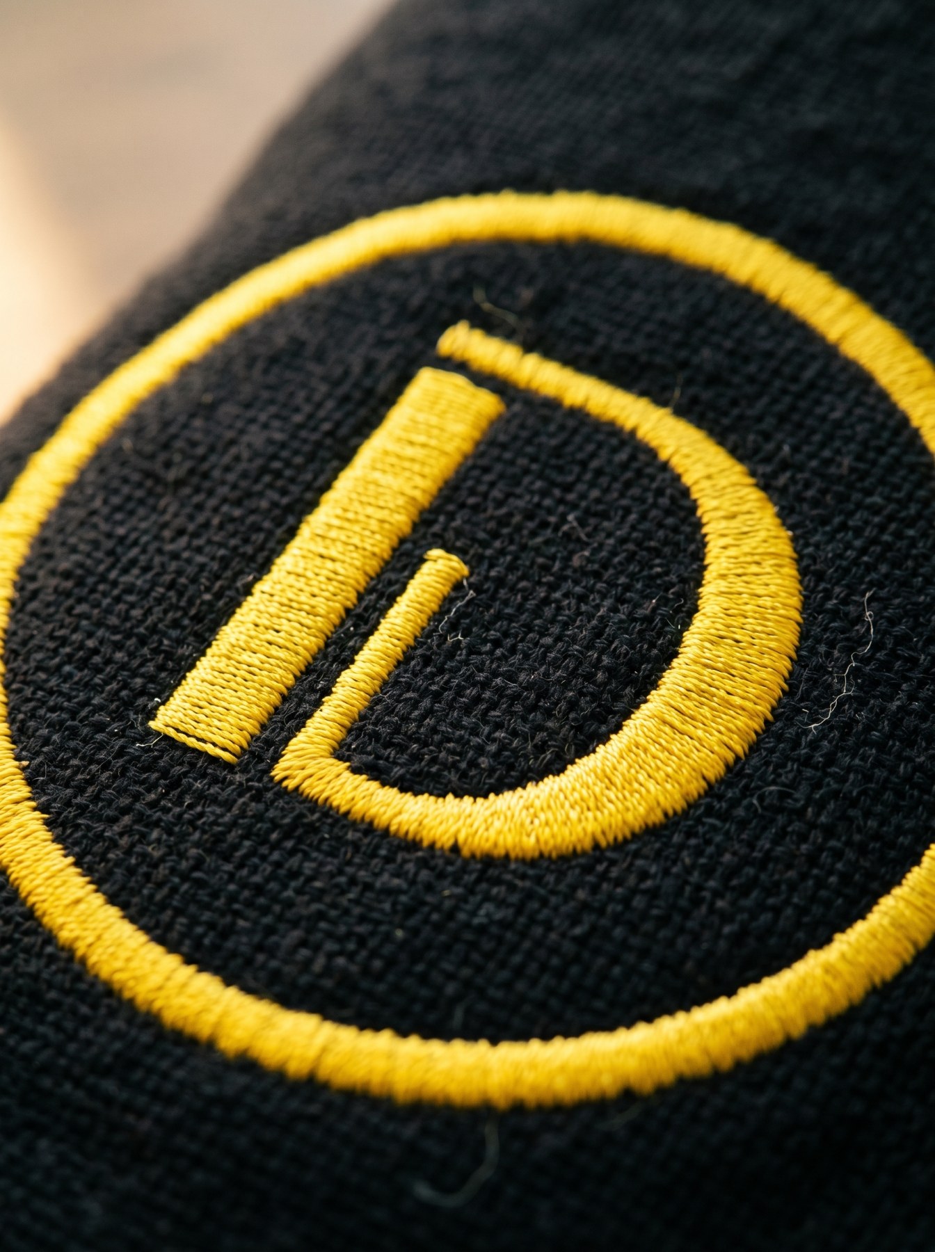 Macro do D bordado em fio amarelo