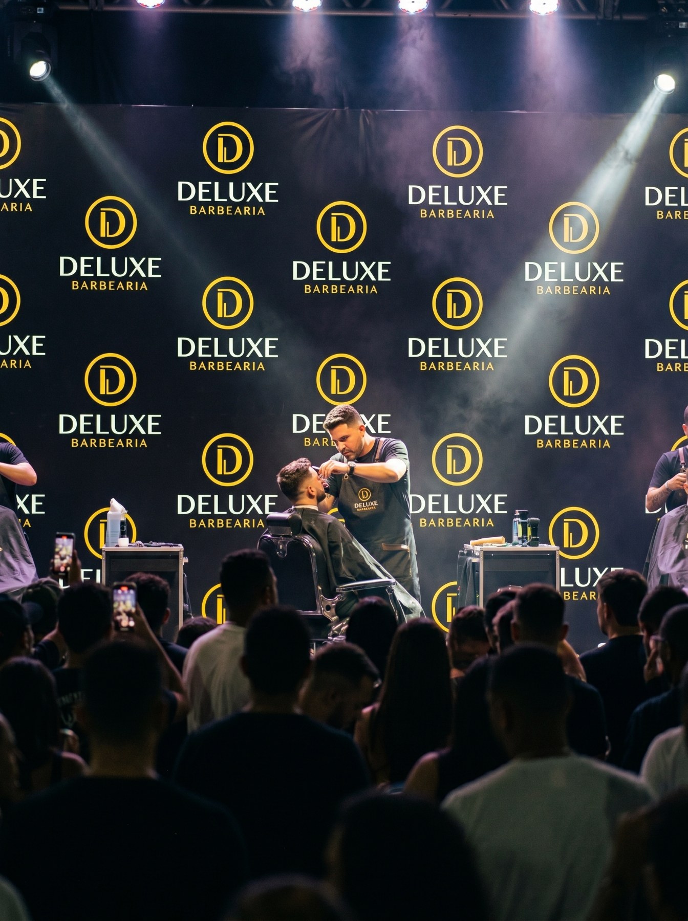 Palco de evento com o backdrop da Deluxe Barbearia